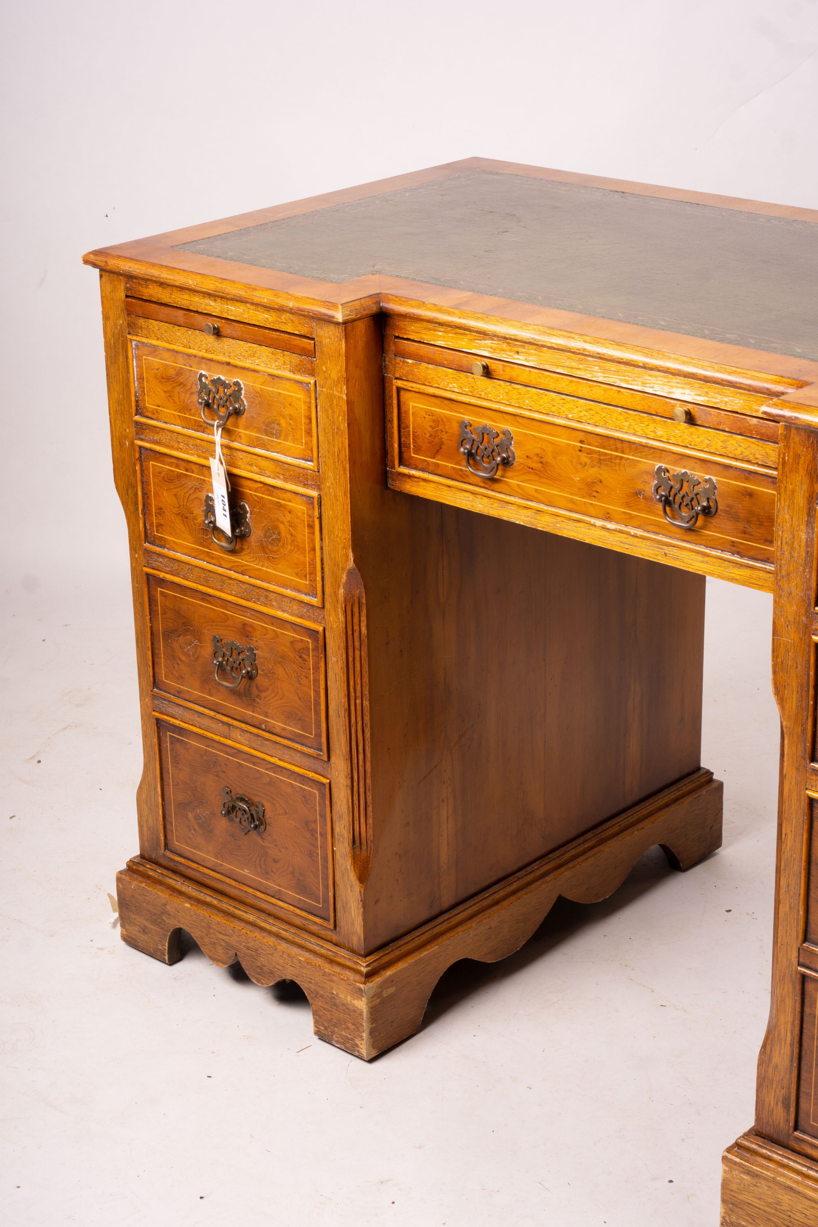 A reproduction yew inverse breakfront kneehole pedestal desk fitted green skiver, width 114cm, depth 58cm, height 77cm